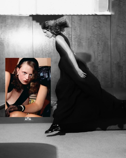 Woman in black gown, side profile, with framed photograph of seated woman wearing black band and gloves, set against a wall background.