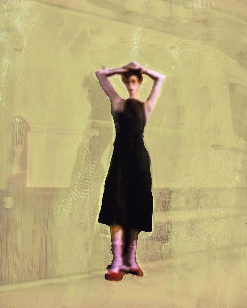 A woman stands with her arms above her head, wearing a black dress and pink boots, set against a yellowish-tan background.