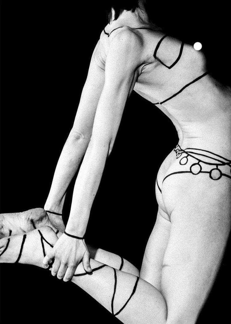 Monochrome art photo of a slender woman with body painting in a pose against a black backdrop, showcasing minimalist aesthetic.