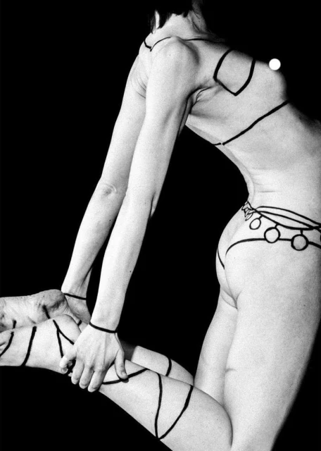 Monochrome art photo of a slender woman with body painting in a pose against a black backdrop, showcasing minimalist aesthetic.