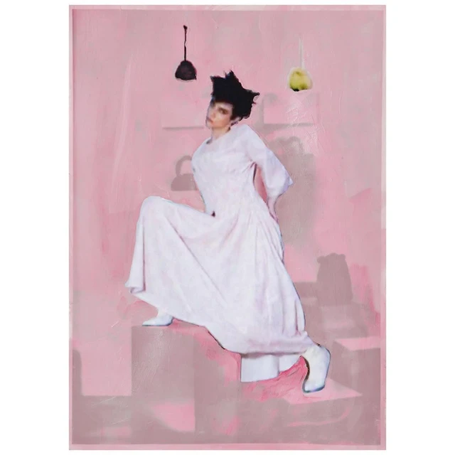 A woman in a long white dress poses on geometric stairs against a pink background with hanging decorative elements above.