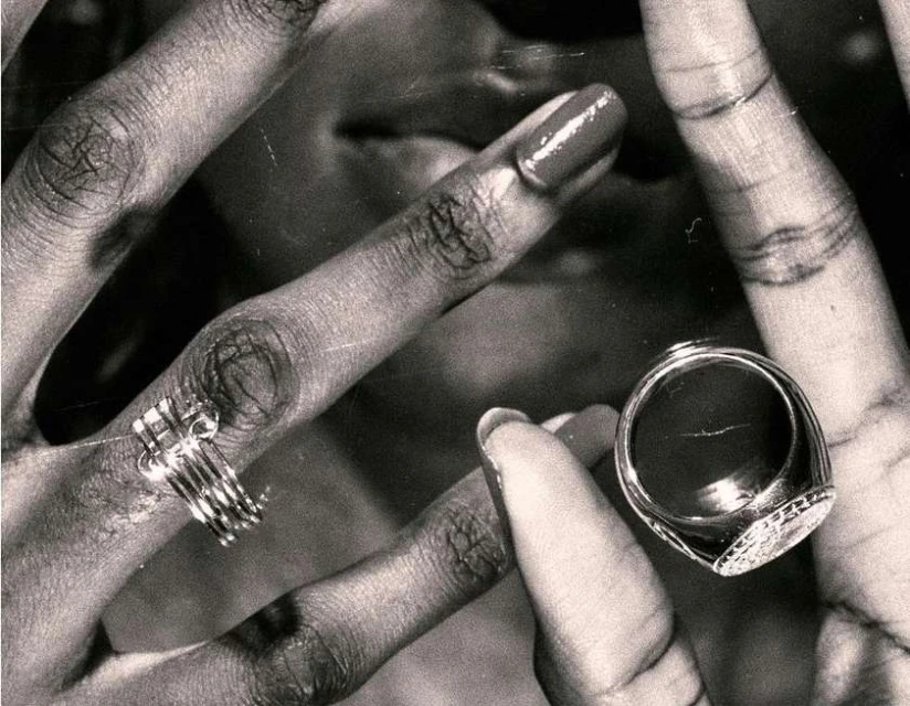 Close-up of an adult's hands with rings, showcasing jewelry on fingers, black and white tones, and well-manicured nails.