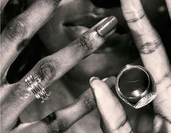 Close-up of an adult's hands with rings, showcasing jewelry on fingers, black and white tones, and well-manicured nails.