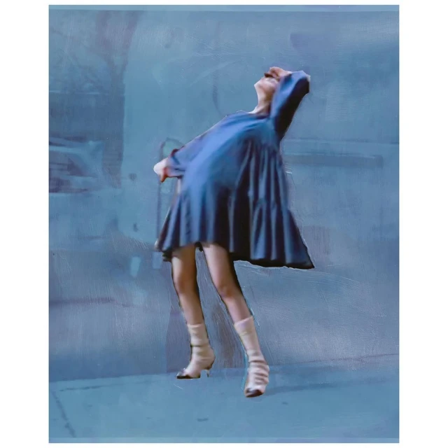 A woman with pale skin, wearing a blue dress and light-colored boots, stands with her head tilted back, captured against a muted blue background.