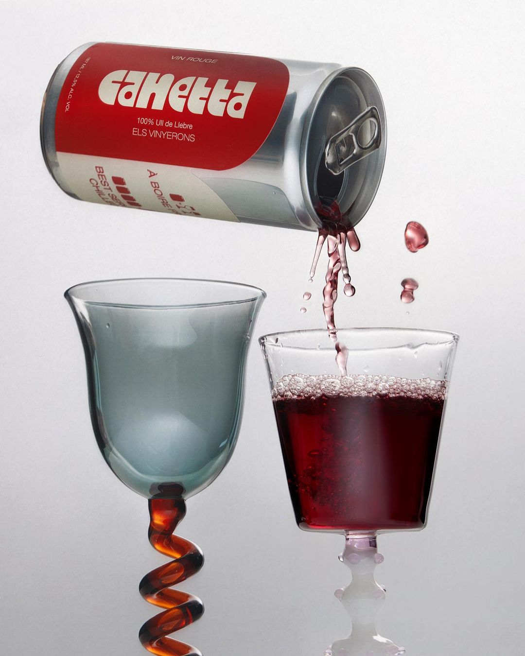 Wine can being poured into two glasses, featuring a red liquid and light background, capturing the essence of a beverage still life.