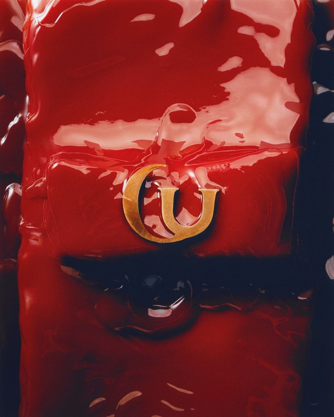 Red-lacquered, glossy handbag with golden logo hardware, captured in a close-up studio shot, highlighting its vibrant color and texture.