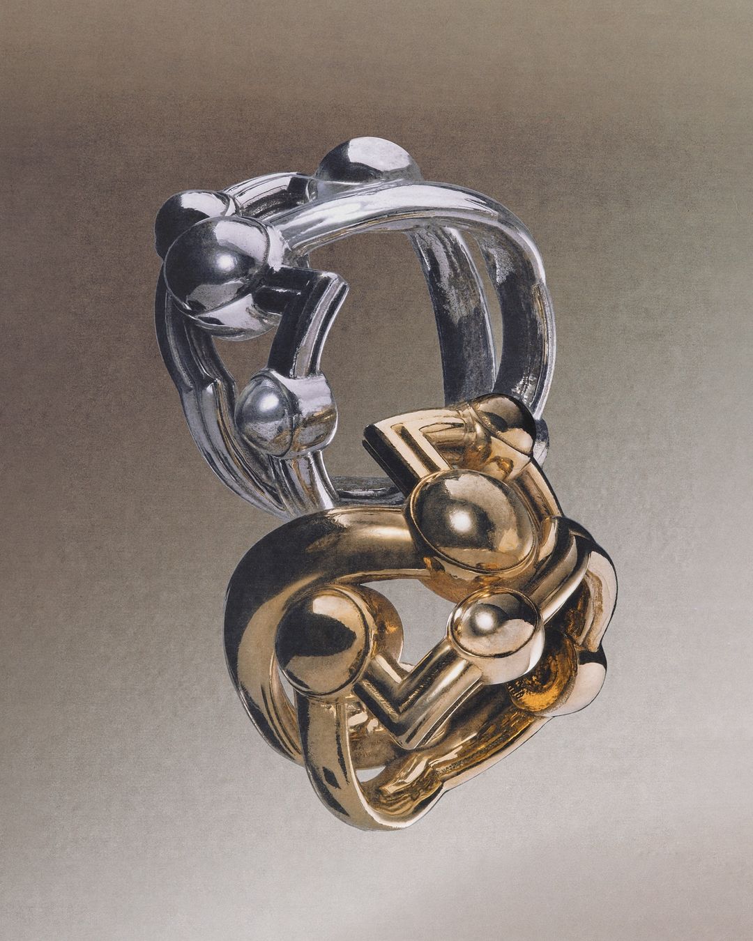 Intricate silver and gold interlocking puzzle rings against a soft gray background. Jewelry design, three-dimensional art, and fine craftsmanship.