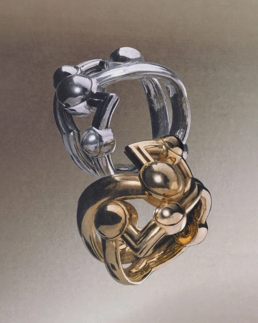 Intricate silver and gold interlocking puzzle rings against a soft gray background. Jewelry design, three-dimensional art, and fine craftsmanship.