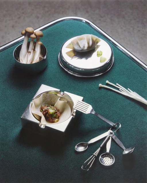 Food still life featuring plated mushrooms, a dumpling, and a savory dish on a table, presented in a studio setting with controlled lighting.