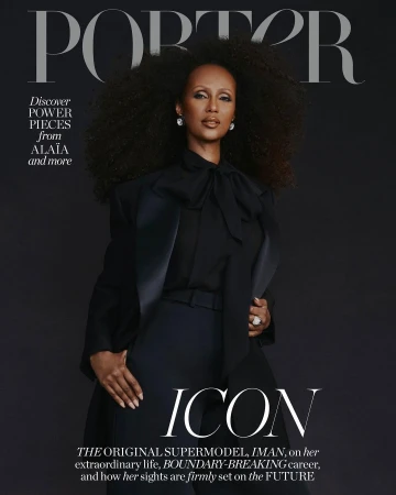 Magazine cover featuring Iman in black suit, large natural hair, diamond earrings and ring, standing against a solid dark backdrop.