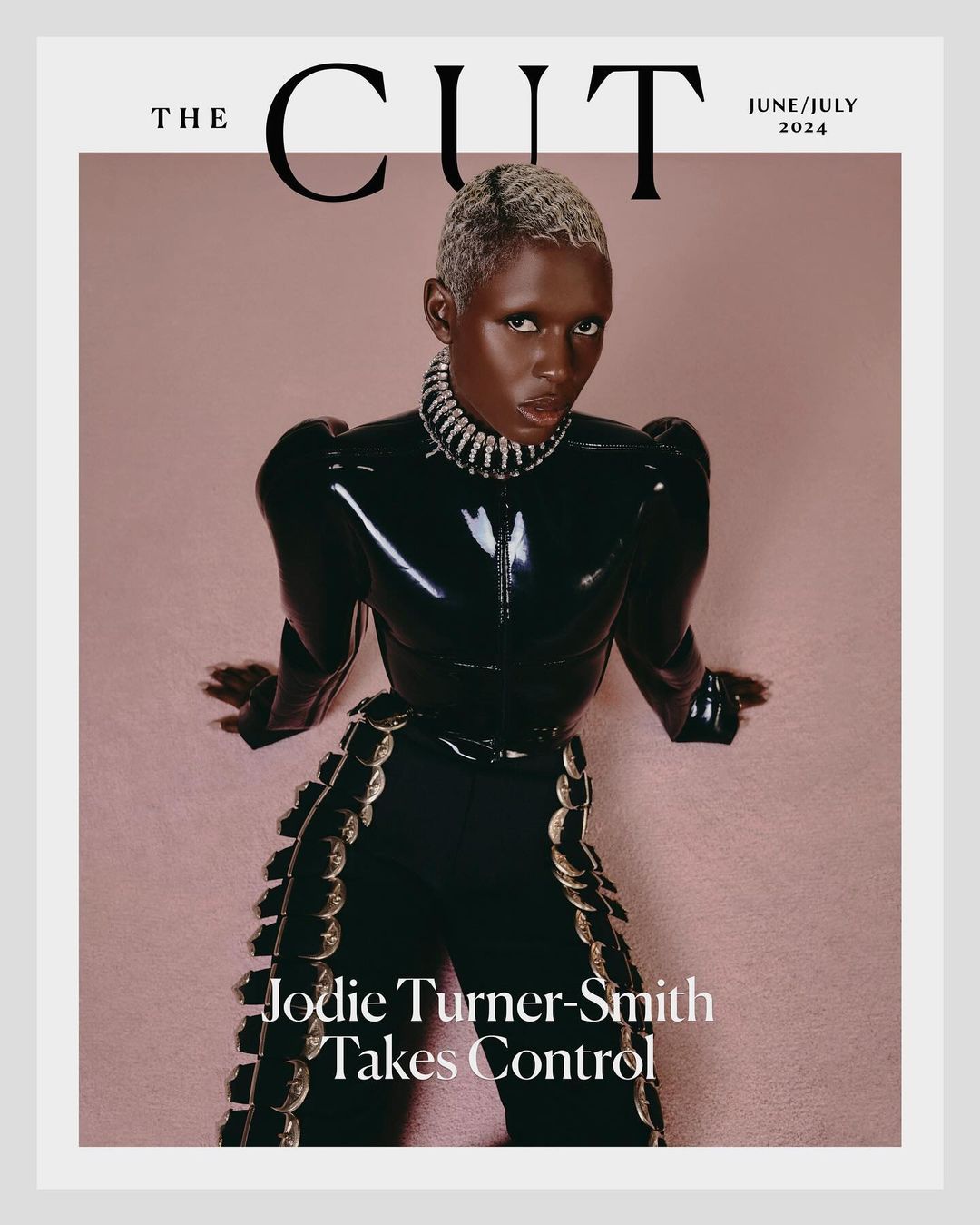 Magazine cover featuring Jodie Turner-Smith in a shiny black outfit and silver jewelry against a light pink backdrop with white trim.