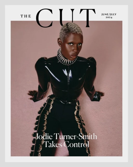 Magazine cover featuring Jodie Turner-Smith in a shiny black outfit and silver jewelry against a light pink backdrop with white trim.