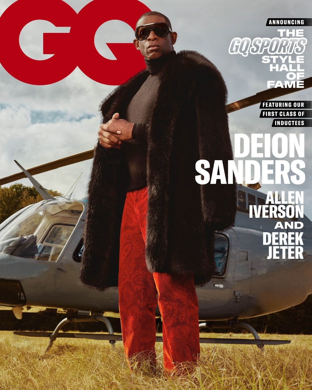 GQ magazine cover featuring Deion Sanders in fur coat and sunglasses, with a helicopter in the background on a grassy field.