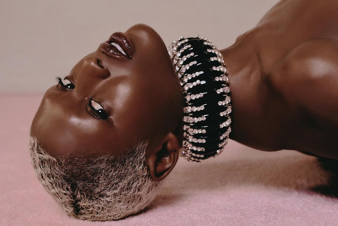 Striking portrait of a Black woman with platinum blonde hair and a jeweled black choker, captured in a close-up studio shot.