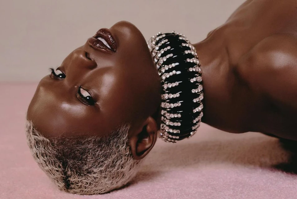 Striking portrait of a Black woman with platinum blonde hair and a jeweled black choker, captured in a close-up studio shot.