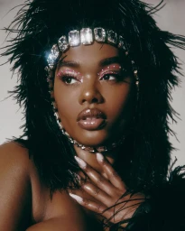 Portrait of a black woman wearing a crystal headband and black feathered garment by Adrienne Raquel.