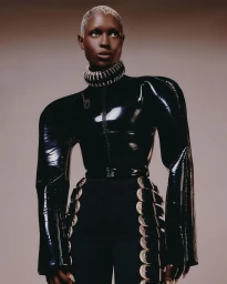 Model with short platinum blonde hair wearing a glossy black latex top and embellished collar by Adrienne Raquel