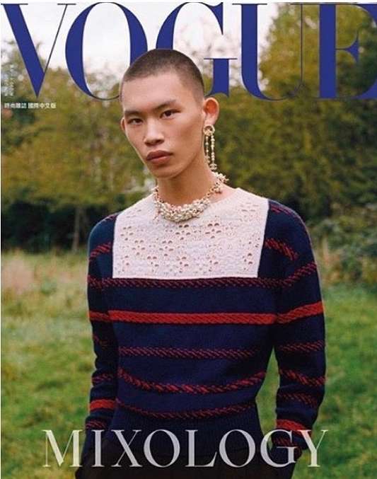 Vogue magazine cover featuring a person with short hair wearing a striped sweater, lace collar, and pearl jewelry in a grassy outdoor setting.