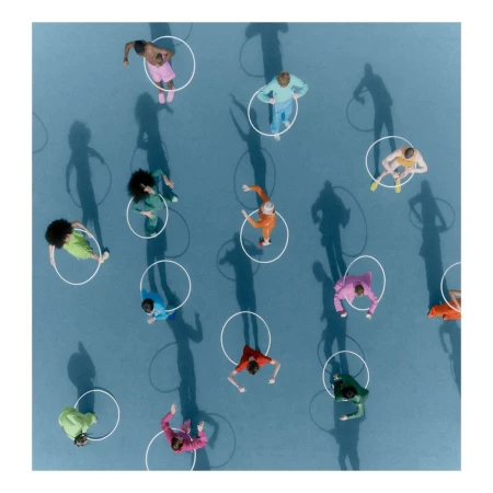 Overhead shot of diverse people in colorful clothing standing inside white circles on a blue surface with shadow casting.