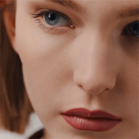 Close-up portrait of a woman with blue eyes and muted red lipstick photographed by Agnes Lloyd-Platt