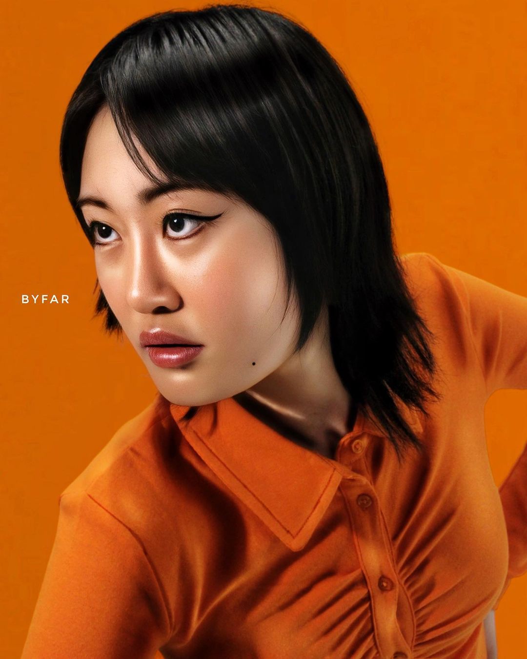 Asian woman with black hair poses in an orange collared shirt against an orange backdrop for a portrait-style fashion photograph.