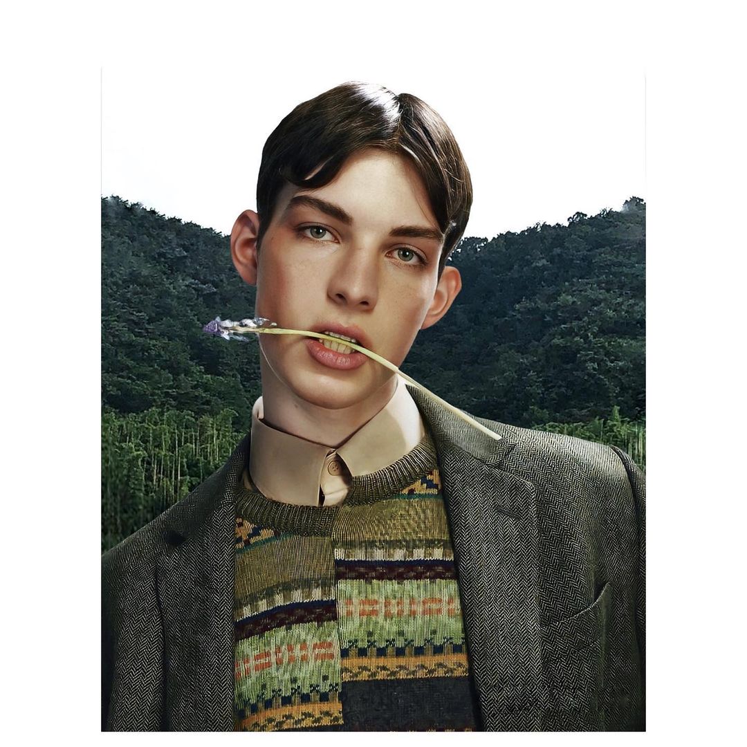 Portrait of a young adult male with dark hair, wearing a tweed jacket and patterned sweater, holding a purple flower in his mouth outdoors.