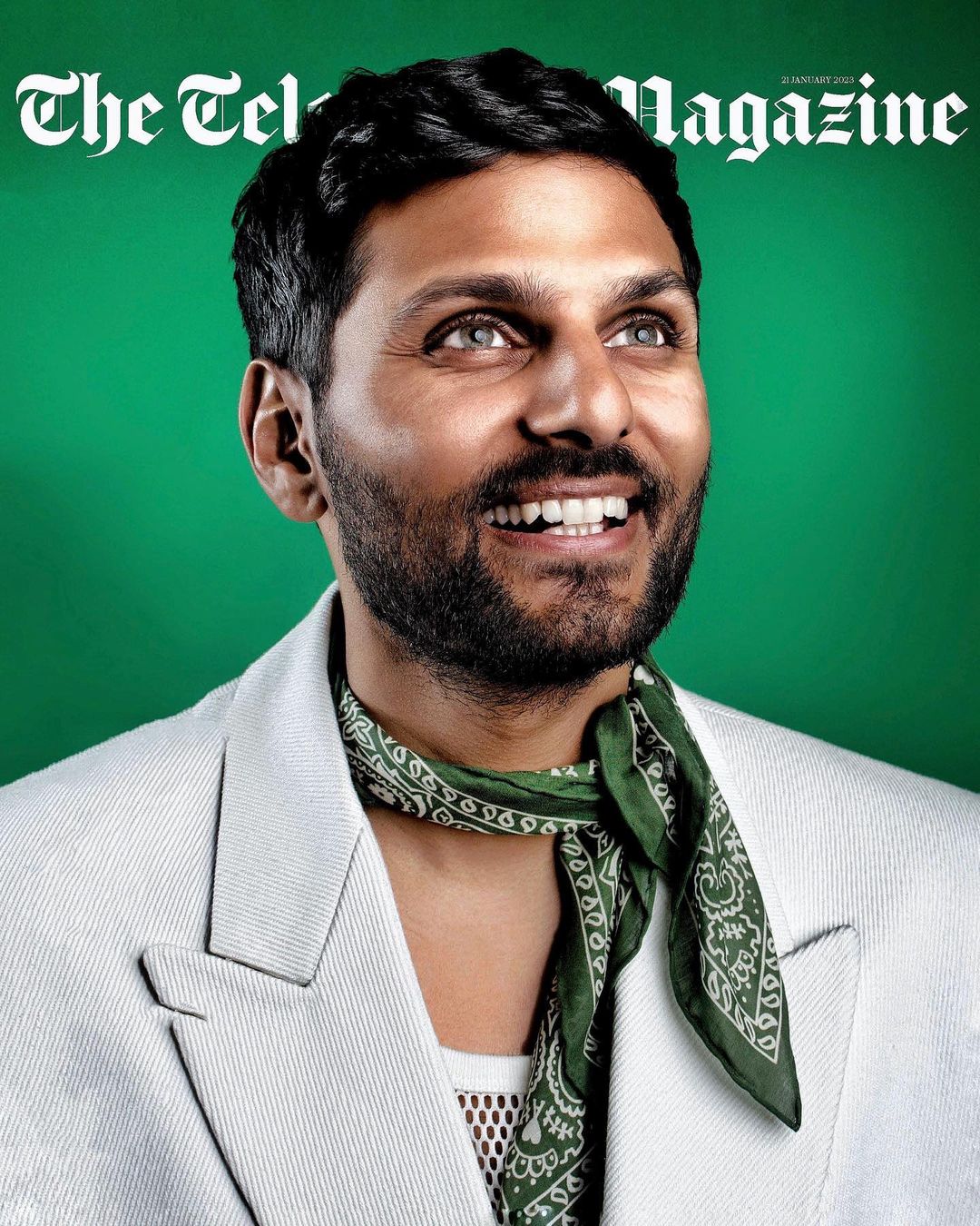 Magazine cover featuring a portrait of an adult man with dark hair, wearing a white suit and green bandana, against a green backdrop.