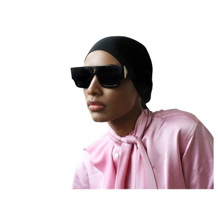 Model wearing oversized black sunglasses and a pink silk blouse against a clean white background