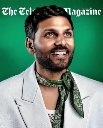 Portrait of a smiling man wearing a white blazer and green patterned neck scarf against a vibrant green background.