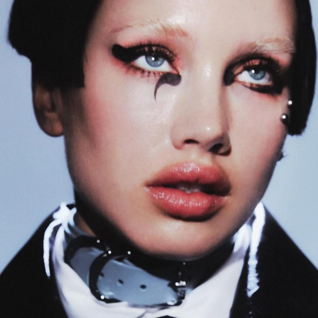 Close-up portrait of a woman with dramatic black eyeliner and a white collar, with focus on beauty, makeup, and fashion.
