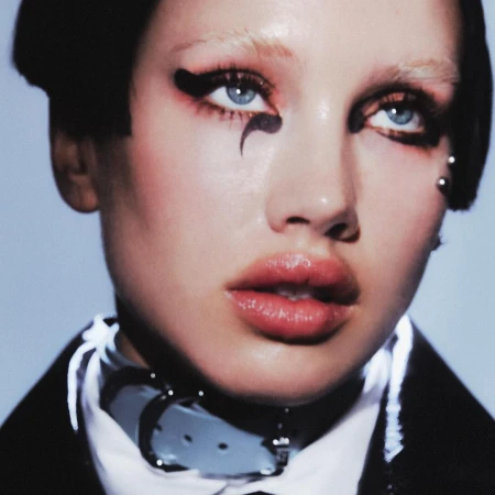 Close-up portrait of a woman with dramatic black eyeliner and a white collar, with focus on beauty, makeup, and fashion.