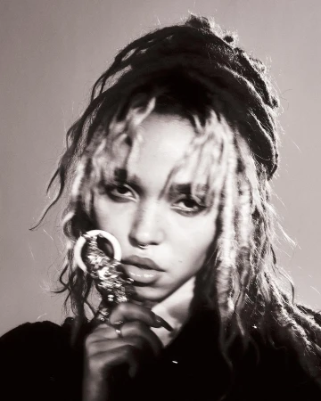Monochrome portrait of a young adult woman with dreadlocks holding an ornamental ring, showcasing a fine-art beauty aesthetic.