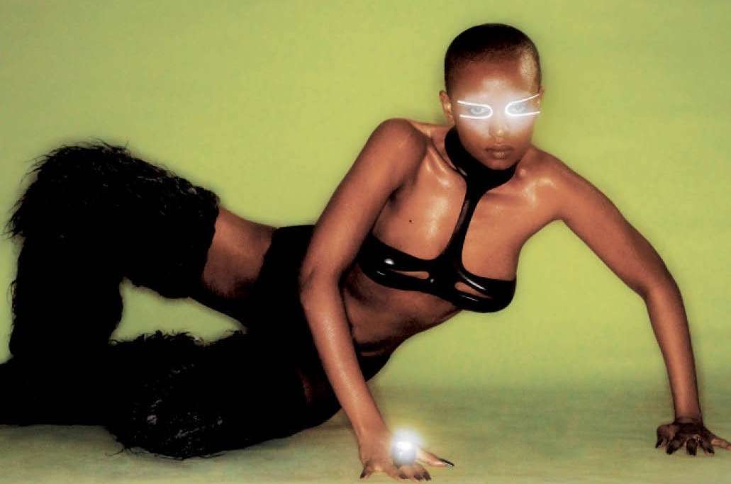 Striking fashion portrait of a Black woman in a futuristic outfit with glowing eyewear, posed against a vibrant lime green background.