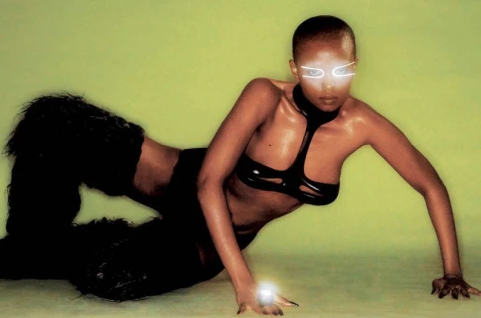 Striking fashion portrait of a Black woman in a futuristic outfit with glowing eyewear, posed against a vibrant lime green background.