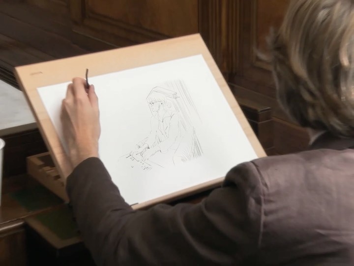 Artist working on a drawing of a person in an indoor setting, utilizing a thin brush to create details on white paper.