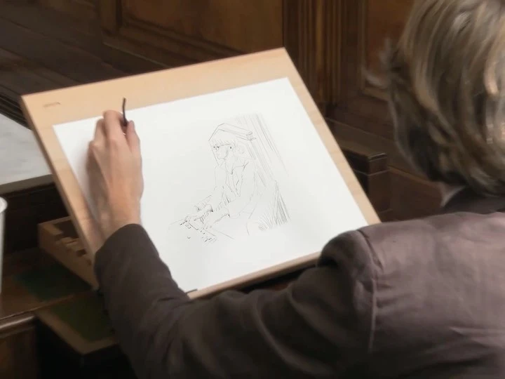 Artist working on a drawing of a person in an indoor setting, utilizing a thin brush to create details on white paper.