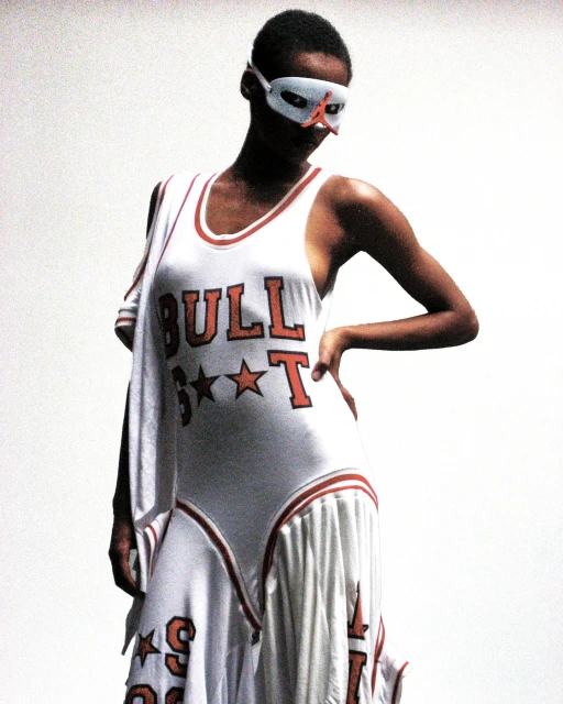 An adult female poses in a white dress with the word 'Bulls' printed on it, complemented by a red and white mask.