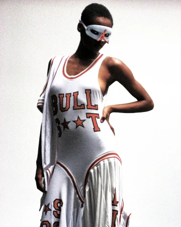 An adult female poses in a white dress with the word 'Bulls' printed on it, complemented by a red and white mask.