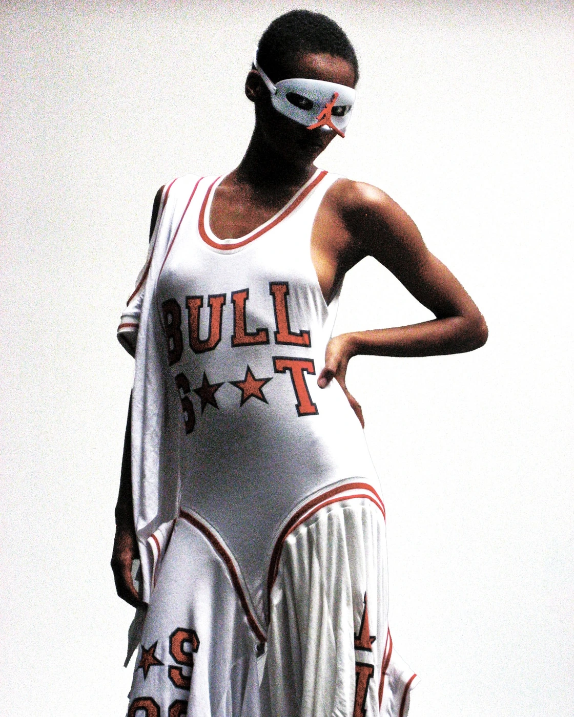 Model wearing white and red athletic dress with typography and a white mask by photographer Aidan Zamiri.