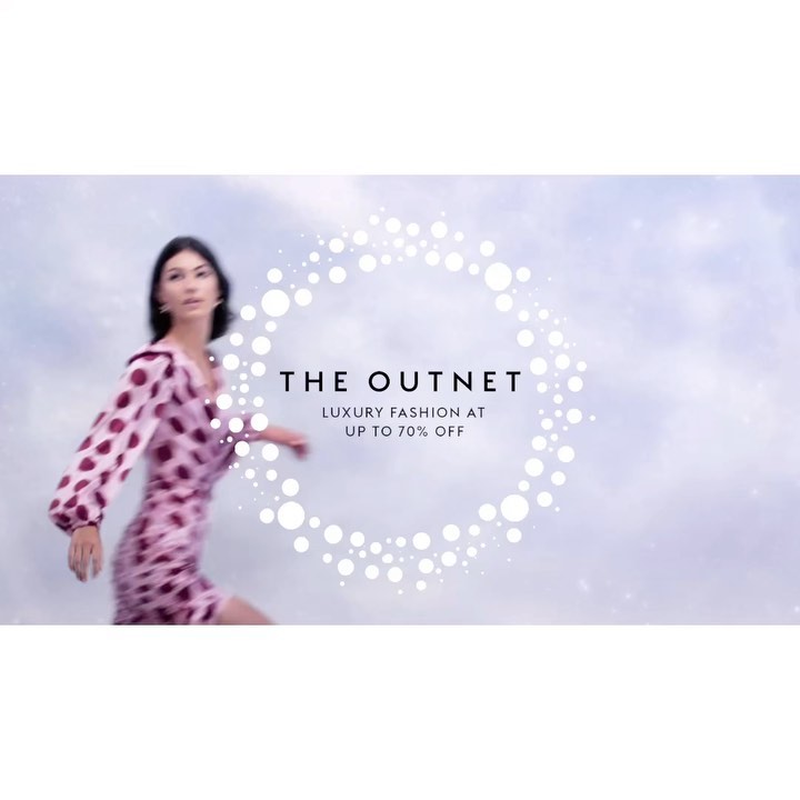 Fashionable adult female model in motion wearing a patterned mini dress against a light blue sky, with an advertisement circle.