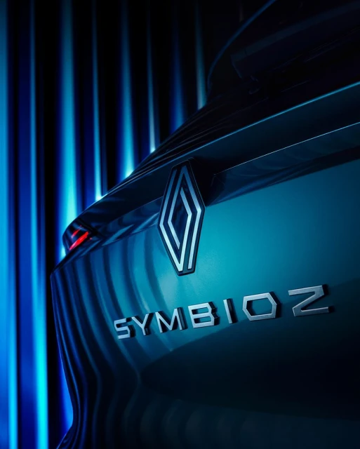 Car tail light detail featuring a Renault logo and the word 'SYMIOZ' in silver lettering, set against a background of blue vertical lighting.