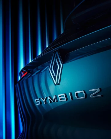 Car tail light detail featuring a Renault logo and the word 'SYMIOZ' in silver lettering, set against a background of blue vertical lighting.