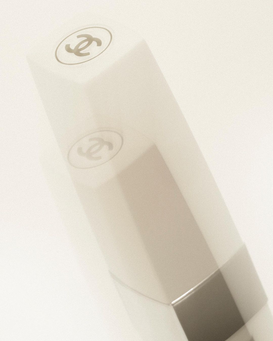 Close-up of Chanel lipstick in white packaging with iconic logo on top, presented against a clean, bright white backdrop.