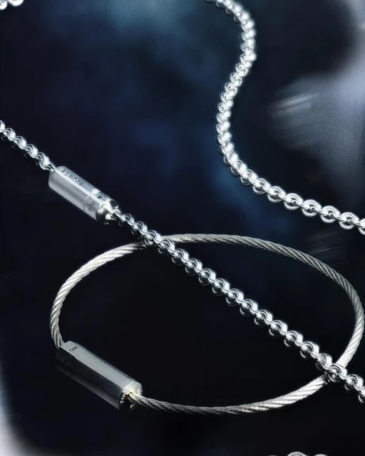 Silver chain and wire necklaces arranged on a dark blue gradient background, showcasing jewellery design and metallic textures in a studio setting.