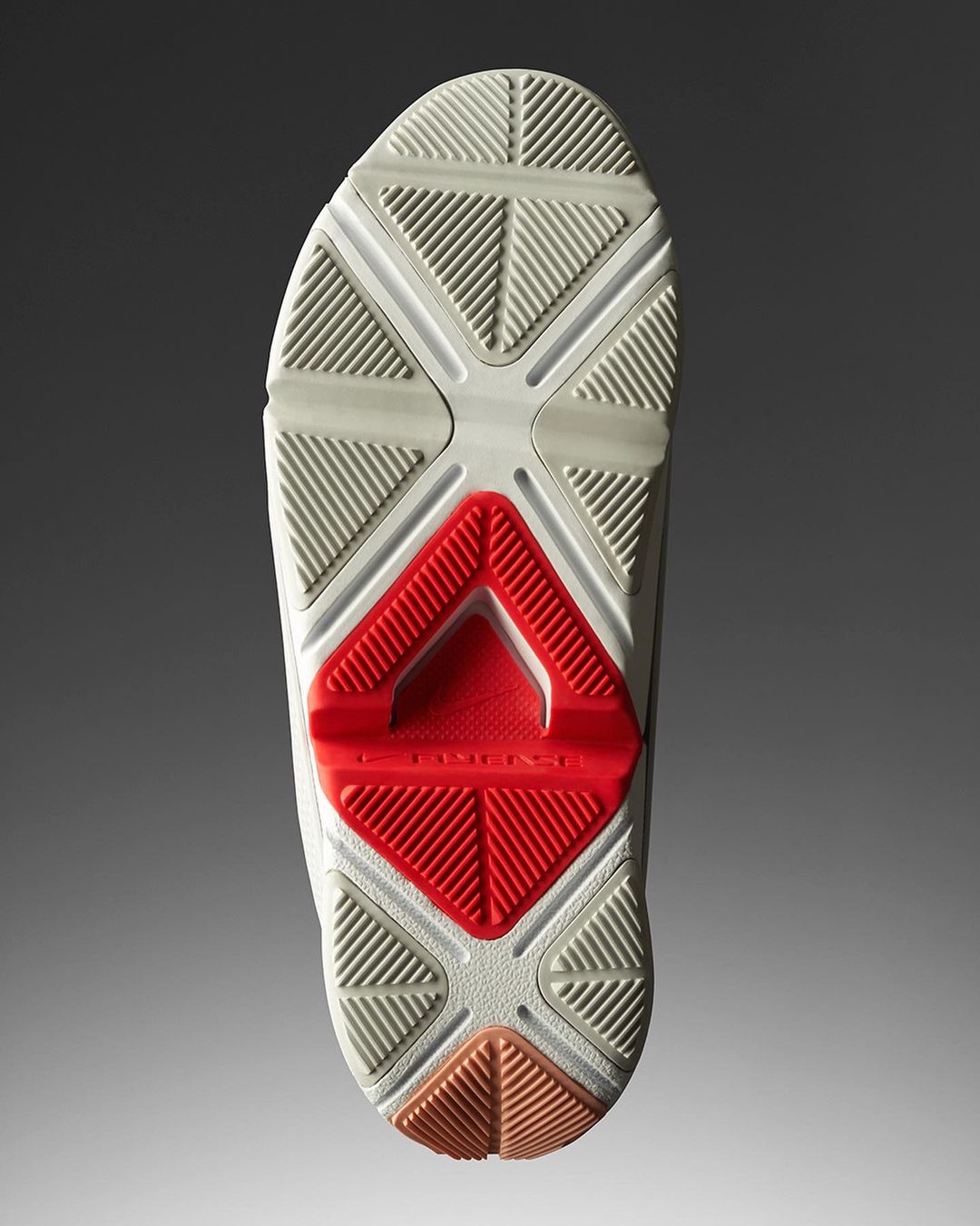 Bottom view of a white shoe sole with a red support structure, featuring a geometric tread pattern and gray gradient background.