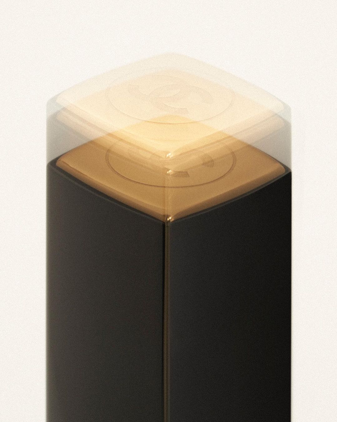 Close-up of a black and gold cosmetic product with a clear cap on a white background, showcasing beauty and makeup.