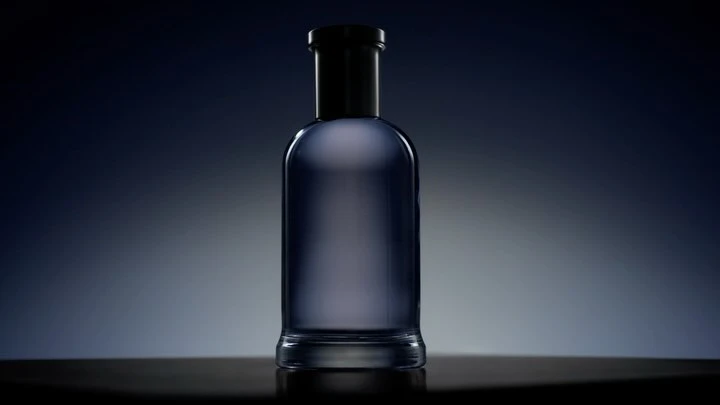 Elegant glass bottle with a black top on a reflective surface, set against a gradient blue background for a sophisticated product shot.