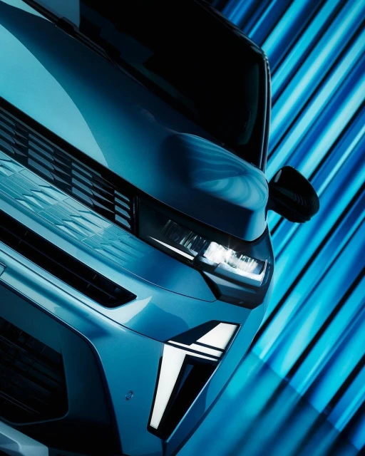Front view of a blue car with its headlights on, showcasing its modern design against a dynamic blue background, automotive photography.