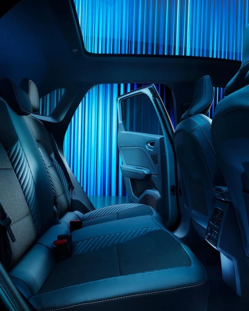 Car interior featuring black leather seats and an open door, illuminated by blue lighting, creating a sleek and modern automotive aesthetic.