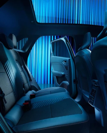 Car interior featuring black leather seats and an open door, illuminated by blue lighting, creating a sleek and modern automotive aesthetic.